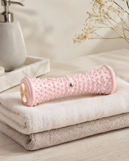 Rouleau de massage pour pieds rose posé sur des serviettes